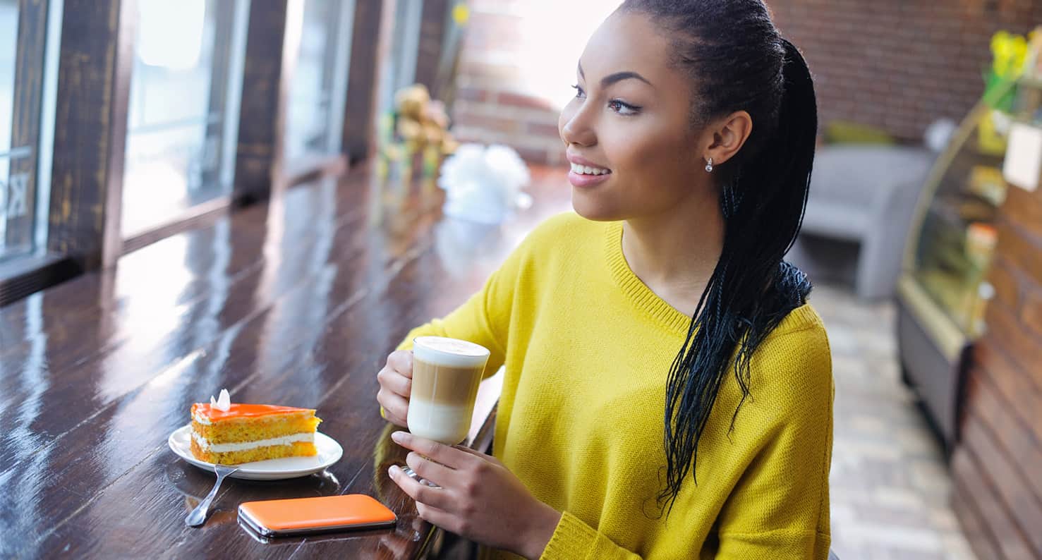  Smiling woman in yellow sweater at cafe.