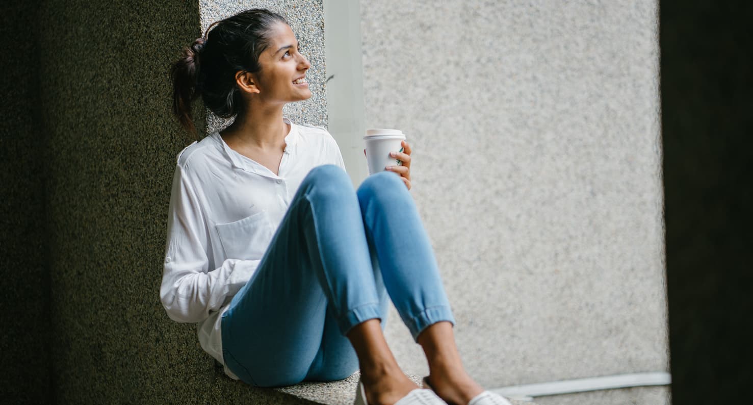 young adult woman drinking coffee outside