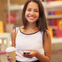 woman smiling with a cup of coffee and smartphone