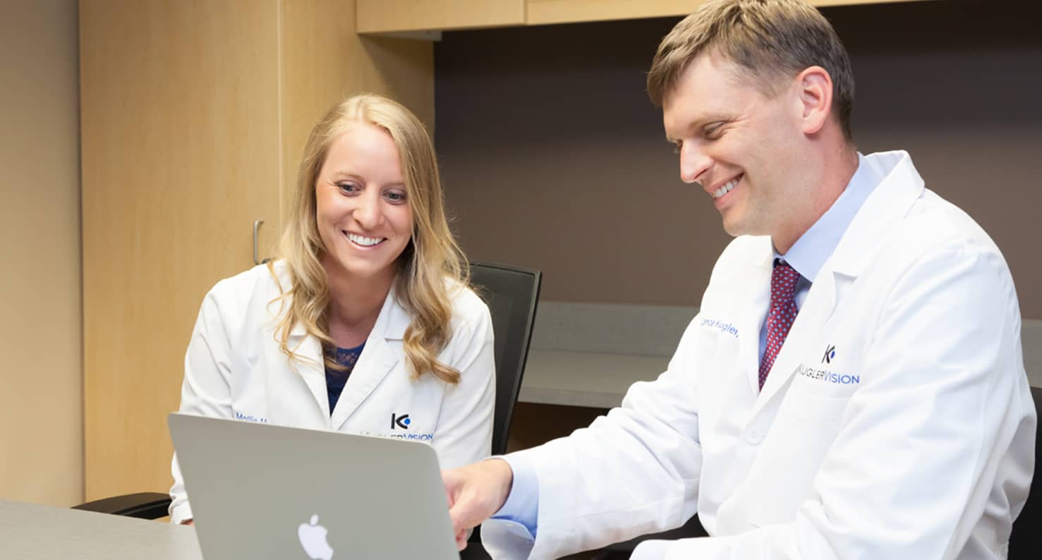 dr mollie hiatt and dr lance kugler of kugler vision looking at an apple macbook