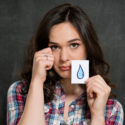sad young adult woman holding a tear card