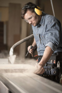 Woodworker wearing muffs and glasses
