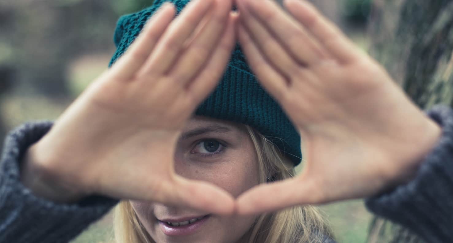 woman looking through hands making a triangle