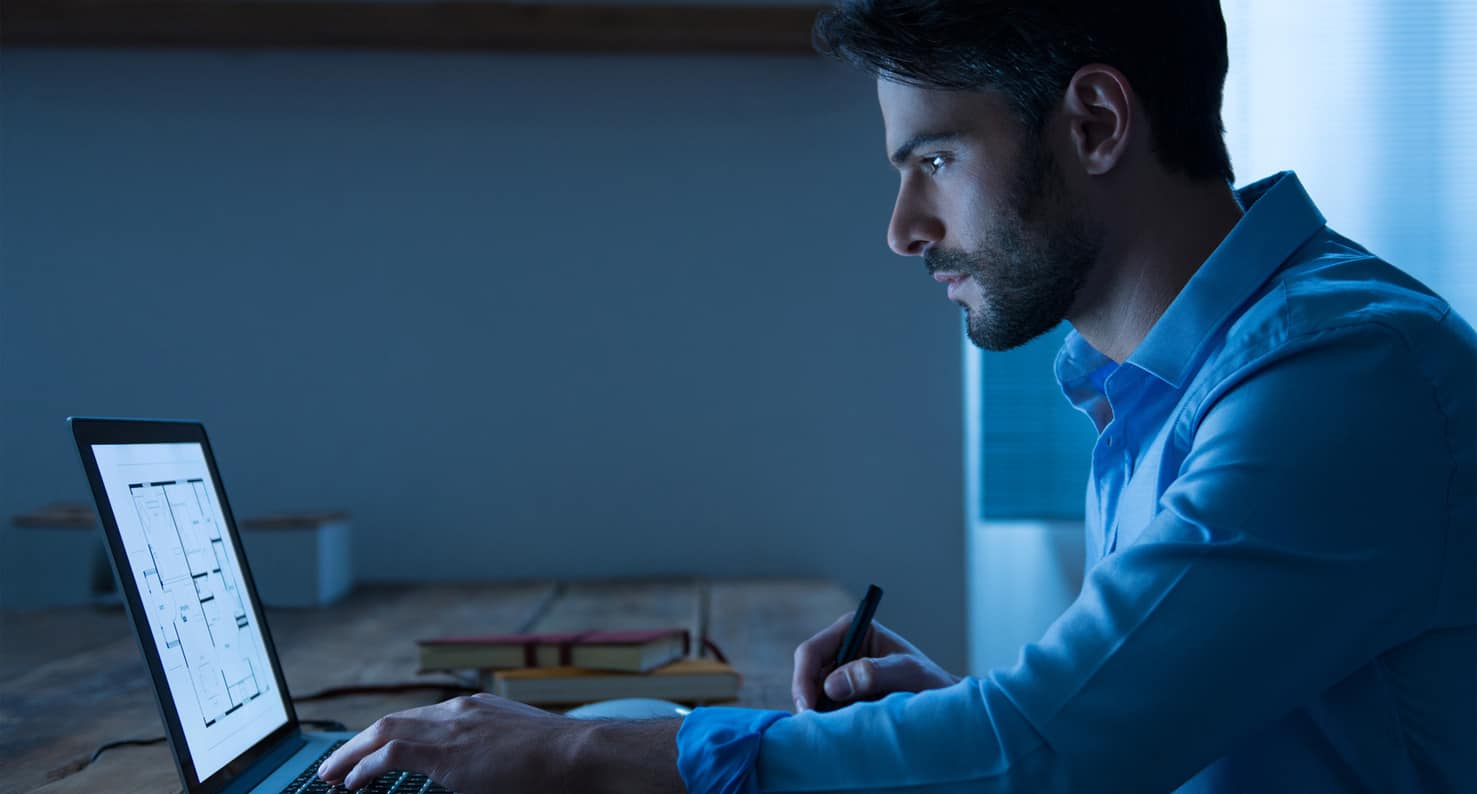 man looking at laptop in low light