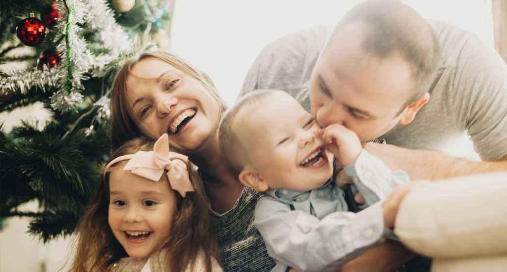 A happy family laughs and cuddles on Christmas morning